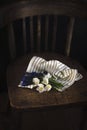 Bouquet of spring white and blue flowers wrapped in light striped fabric on a vintage wooden chair. Dark background. Top view. Royalty Free Stock Photo