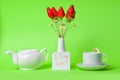 A bouquet of strawberries in a white vase and a small card on a green background.ÃÂ¡up of tea with chamomile and teap