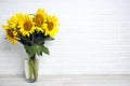 A bouquet of sunflowers in a vase against the background of a white brick wall Royalty Free Stock Photo