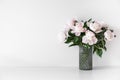 Bouquet of tender pink peonies in vase near white wall Royalty Free Stock Photo
