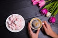 Bouquet of tender pink tulips and hands holding cup of coffee an