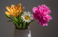 A bouquet of three different flowers in a vase on a grey background. Royalty Free Stock Photo