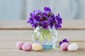 Bouquet of tiny violets viola odorata and chocolate Easter eggs on wooden table