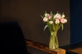 A bouquet of tulips of different colors, white, pink, stands in a glass vase in a dark interior. Royalty Free Stock Photo