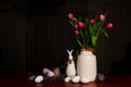 A bouquet of tulips, Easter bunny and eggs on wooden table on Scandinavian-style kitchen. Easter night