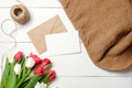 Bouquet of tulips flowers, kraft envelope, twine, burlap on white wooden table. Vintage greeting card for womans day, mothers day, Royalty Free Stock Photo