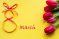 Bouquet of tulips and the inscription March 8 on a yellow background. Congratulations on the International Women`s Day, March 8th