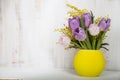 Bouquet of tulips and mimosa in a yellow vase on a wooden background. Royalty Free Stock Photo