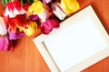 Bouquet of tulips and white mockup frame on wooden background. Easter or Birth Day greeting mock up.