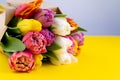 A bouquet of tulips wrapped in craft paper. Spring flowers. Gift delivery. Celebration. Copy space. Yellow, white, pink, purple Royalty Free Stock Photo