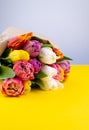 A bouquet of tulips wrapped in craft paper. Spring flowers. Gift delivery. Celebration. Copy space. Yellow, white, pink, purple Royalty Free Stock Photo