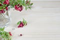Bouquet of twigs with red ripe lingonberries in glass on wooden background. traditional vegetation of North America, Scandinavia