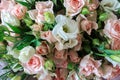 a bouquet of a variety of beautiful flowers like shrub roses and lisianthus eustoma on a wooden surface