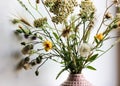 Bouquet of various wildflowers in a pink vase in home interior. Cosy atmosphere.