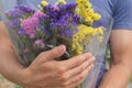 Bouquet of violet, yellow, pink and white statis in the man`s hands Royalty Free Stock Photo