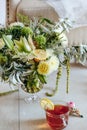 A bouquet of white asters, green lilies and other flowers, decorated with lemons, a cup of tea with a slice of lemon on the table Royalty Free Stock Photo