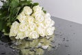 A bouquet of white beige 19 roses with water drops on a mirror table with a snow, ice and beautiful reflection. Symbol of love and Royalty Free Stock Photo