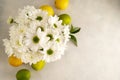 Bouquet of white chrysanthemums in glasswith whole lemons and limes. Abstract floral and fruits rustic background.
