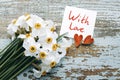 Bouquet of white daffodils, two decorative hearts and a card with the inscription WITH LOVE on the background of an old wooden sur Royalty Free Stock Photo