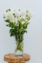 Bouquet of white dahlia flowers in glass vase on an wood vintage stool against the white wall Royalty Free Stock Photo