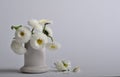 A bouquet of white daisies in a white ceramic pile