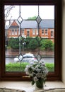 A bouquet of white flowers on the windowsill against the backdrop of a rainy day on a typical english street Royalty Free Stock Photo