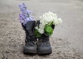 Bouquet of white and lilac flowers in dirty soldier`s boots in the spring garden Royalty Free Stock Photo