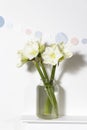 Bouquet of white lilies in a tall glass vase on a beige table against a gray wall. Copy space Royalty Free Stock Photo
