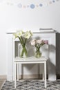 Bouquet of white lilies in a tall glass vase on a beige table against a gray wall. Copy space. Fresh bud Royalty Free Stock Photo