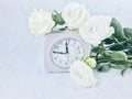 Bouquet of white roses and alarm clock on cool light blue background.