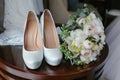 Bouquet of white roses and elegant wedding shoes on wooden table Royalty Free Stock Photo