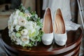 Bouquet of white roses and elegant wedding shoes on wooden table Royalty Free Stock Photo