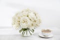 A bouquet of white roses in a glass vase on a table with cups of tea on the table Royalty Free Stock Photo