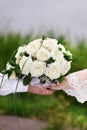 Bouquet of white roses in hand of groom and bride