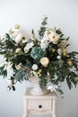 Bouquet of white roses, peonies, dahlias and eucalyptus branches in a ceramic vase on the bedside table Royalty Free Stock Photo
