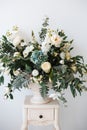 Bouquet of white roses, peonies, dahlias and eucalyptus branches in a ceramic vase on the bedside table Royalty Free Stock Photo