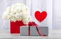 A bouquet of white roses in a red box and a figure of a heart from red paper for inscription on a white background. Royalty Free Stock Photo