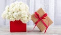 A bouquet of white roses in a red box and a gift box tied with a red ribbon, close-up. Valentine`s day, wedding, declaration of lo Royalty Free Stock Photo