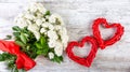 A bouquet of white roses with a red ribbon and two frames of red rattan hearts for an inscription or photo. Royalty Free Stock Photo