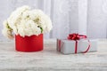 A bouquet of white roses in a red round box and a gift box tied with a red ribbon. Royalty Free Stock Photo