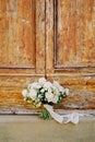 Bouquet of white roses tied with a ribbon stands on the threshold of a wooden door