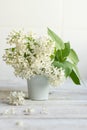 A bouquet of white spring flowers of lilac in a ceramic vase on a light wooden background and on the background of kitchen tiles. Royalty Free Stock Photo