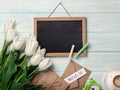 A bouquet of white tulips with chalk board, cup of coffee, love note and envelopes on blue wooden boards . Mother`s day