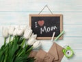 A bouquet of white tulips with chalk board and envelopes on blue wooden boards . Mother`s day