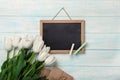 A bouquet of white tulips with chalk board and envelopes on blue wooden boards