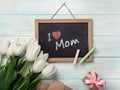 A bouquet of white tulips with chalk board, gift box envelopes on blue wooden boards . Mother`s day