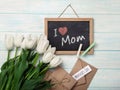 A bouquet of white tulips with chalk board, love note and envelopes on blue wooden boards. Mother`s day