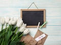 A bouquet of white tulips with chalk board, love note and envelopes on blue wooden boards
