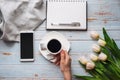 bouquet of white tulips with a Cup of coffee in women& x27;s hands, a smartphone and an empty notebook for text Royalty Free Stock Photo