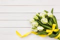Bouquet of white tulips decorated with yellow ribbon on white wooden background Royalty Free Stock Photo